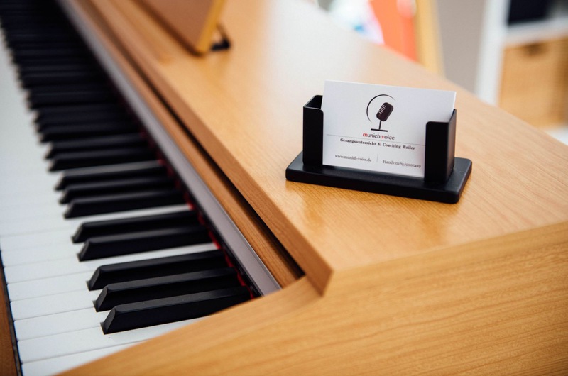 hellbraunes Klavier mit den Visitenkarten und Logo von munich-voice