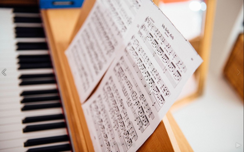 hellbraunes Klavier mit den Noten, im Hintergrund steht ein Spiegel